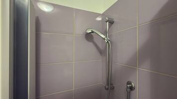 Eine Dusche mit Handbrause und fest installierten Armaturen.
