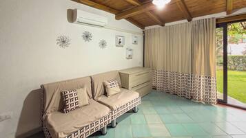 Una habitación con sofá, una mesita y una ventana con cortinas.