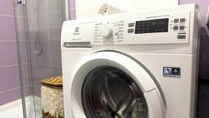 A front-loading washing machine with a control panel, a "Wood Hand Wash Safe" sticker, and a towel on top. - Residenze Cielo e Mare - Conchiglia (San Teodoro)