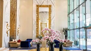 Un hall d’entrée luxueux, doté d’un sol en marbre, d’un grand miroir à cadre doré et d’une paroi en verre offrant une vue sur la ville.