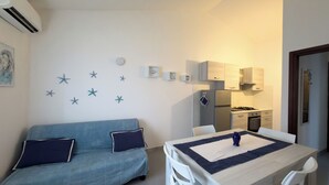 Ein gemütlicher Wohnbereich mit blauem Sofa, Esstisch und Küchenzeile.