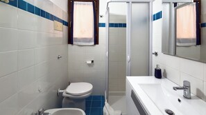 Un baño con inodoro, lavabo y ducha.