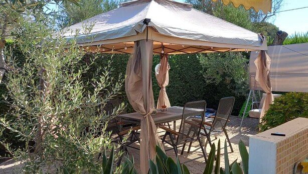 Une terrasse extérieure dotée d’un espace salon abrité, d’une table et de chaises.