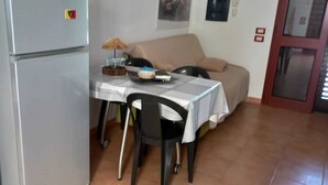 Un espace de vie compact comprenant un coin cuisine, une table à manger avec des chaises, un canapé et un petit meuble de rangement.