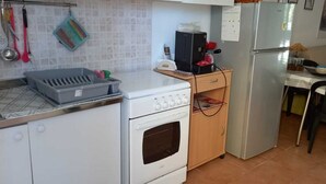 Une cuisine compacte avec un fourneau blanc, un petit four, un réfrigérateur et un coin repas comprenant une table et des chaises.