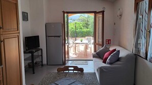 A compact living space with a kitchenette, a sofa, a dining table, and a television. - Residenze Cielo e Mare - Sole (San Teodoro)
