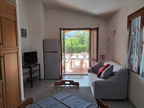 A compact living space with a kitchenette, a sofa, a dining table, and a television. - Residenze Cielo e Mare - Sole (San Teodoro)