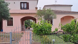 A pink villa with arched doorways, a metal gate, and a vineyard in the foreground. - Residenze Cielo e Mare - Sole (San Teodoro)