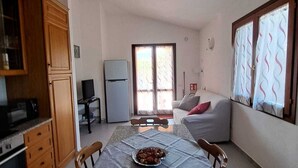 A compact living space with a kitchen, dining area, and a sofa. - Residenze Cielo e Mare - Sole (San Teodoro)