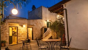 Ein Steinhaus mit Essbereich, Außenbereich und einer Treppe zu einer oberen Ebene.