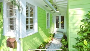 A green house with white trim, a number 542, and a small garden with plants and gravel. - New ! 3-bedroom Pool Home Oasis! Great Location (Sarasota)