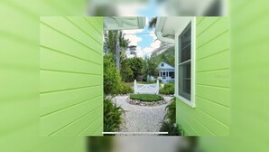 A narrow pathway leading to a house with a white fence and a small garden. - New ! 3-bedroom Pool Home Oasis! Great Location (Sarasota)