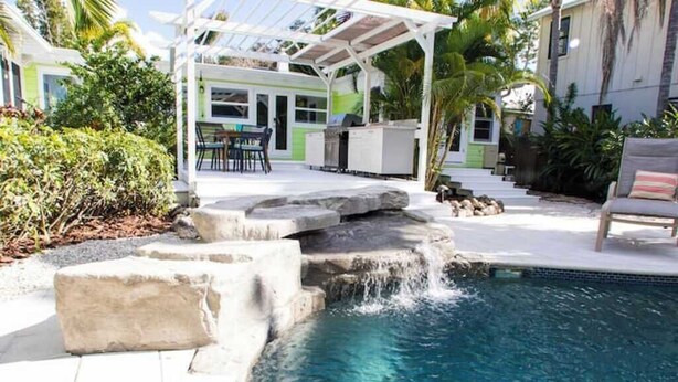 A backyard with a swimming pool, a covered patio, and a grill area. - New ! 3-bedroom Pool Home Oasis! Great Location (Sarasota)