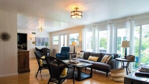 A spacious living room with a sofa set, a coffee table, and a chair. There are two lamps on side tables, and a large window provides natural light. - New ! 3-bedroom Pool Home Oasis! Great Location (Sarasota)