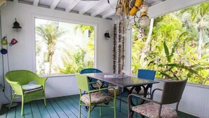 A room with a wooden floor, a table with chairs, and large windows with a view of greenery. - New ! 3-bedroom Pool Home Oasis! Great Location (Sarasota)