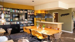 Un comedor moderno con una mesa de madera, sillas de mimbre y una estantería llena de libros.