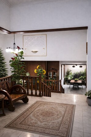 Un intérieur spacieux avec un escalier en bois, un coin repas et un grand tapis.