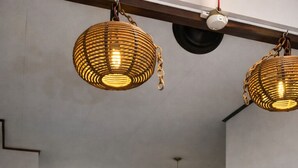 En matplats med ett träbord, flätade hänglampor och en öppen spis.