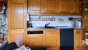 A kitchen with wooden cabinets, a dishwasher, and a coffee maker. - Au bon accueil gîte with covered and fenced swimming pool, garden, hiking trails (Bonnac)