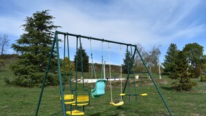 A playground with swings and a yellow bench. - Au bon accueil gîte with covered and fenced swimming pool, garden, hiking trails (Bonnac)