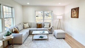 Una sala moderna con un sofá modular, una mesa de centro y una lámpara de pie.