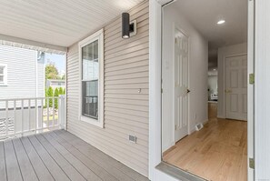 A covered porch with a white railing, a window, and a wall-mounted light fixture. - 3-bedroom condo in fantastic Greenwich  unit A (Greenwich)