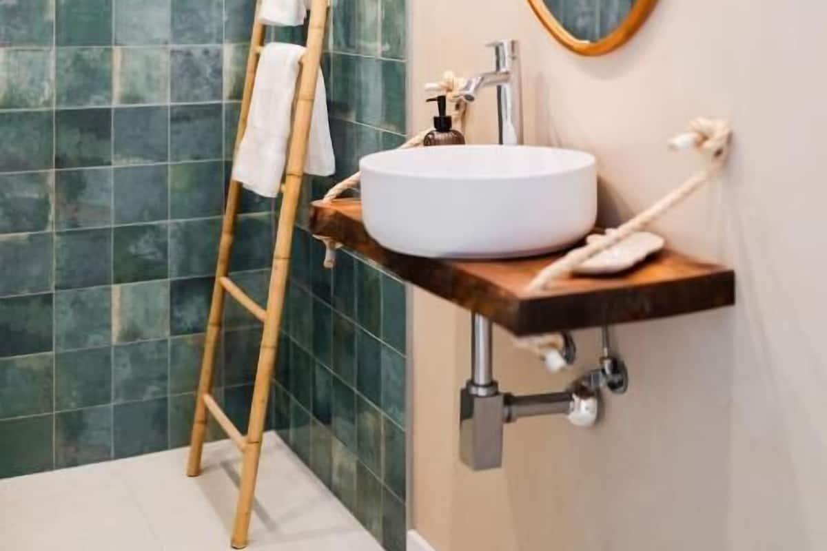 A bathroom with a white sink, a wooden ladder, and a mirror on the wall.