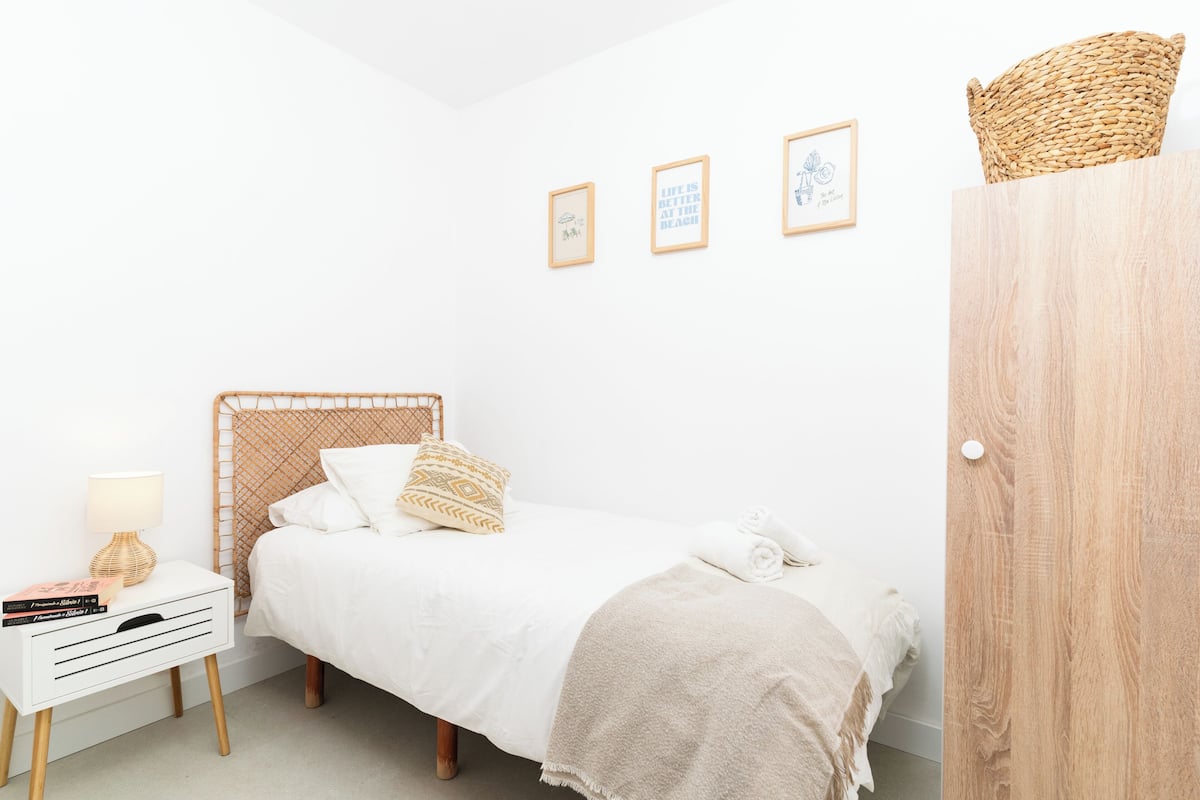 A neatly arranged bedroom with a bed, bedside table, lamp, and wall art.