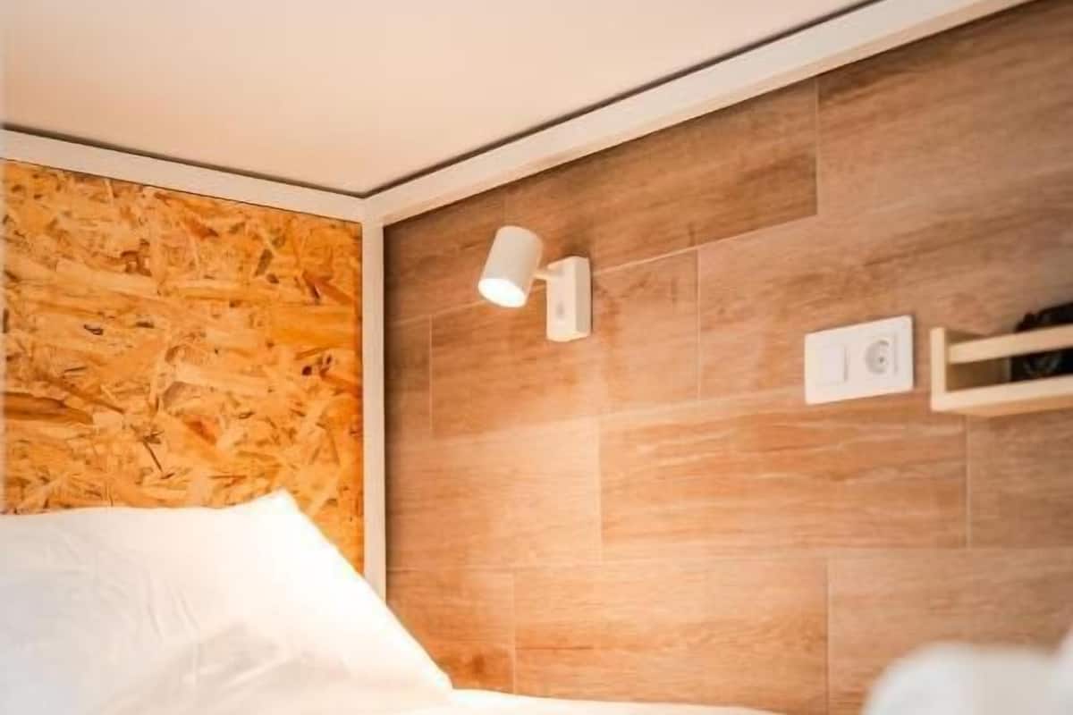 A hotel room with a wooden headboard, a bed with white bedding, and a wall-mounted light fixture.