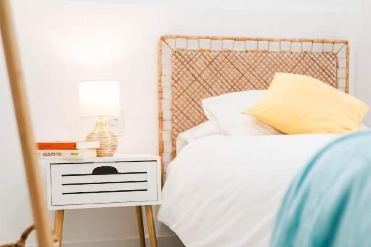 A bedroom with a bed, a bedside table with a lamp, and a chair.