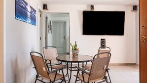 A dining area with a round table, four chairs, a potted plant, and a flat-screen TV mounted on the wall. - Villa Nicolai with Private Pool for up to 20 Guests (Licata)