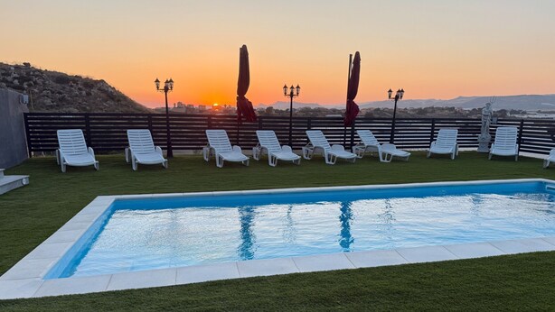 A swimming pool with lounge chairs, a sunset view, and a fence. - Villa Nicolai with Private Pool for up to 20 Guests (Licata)