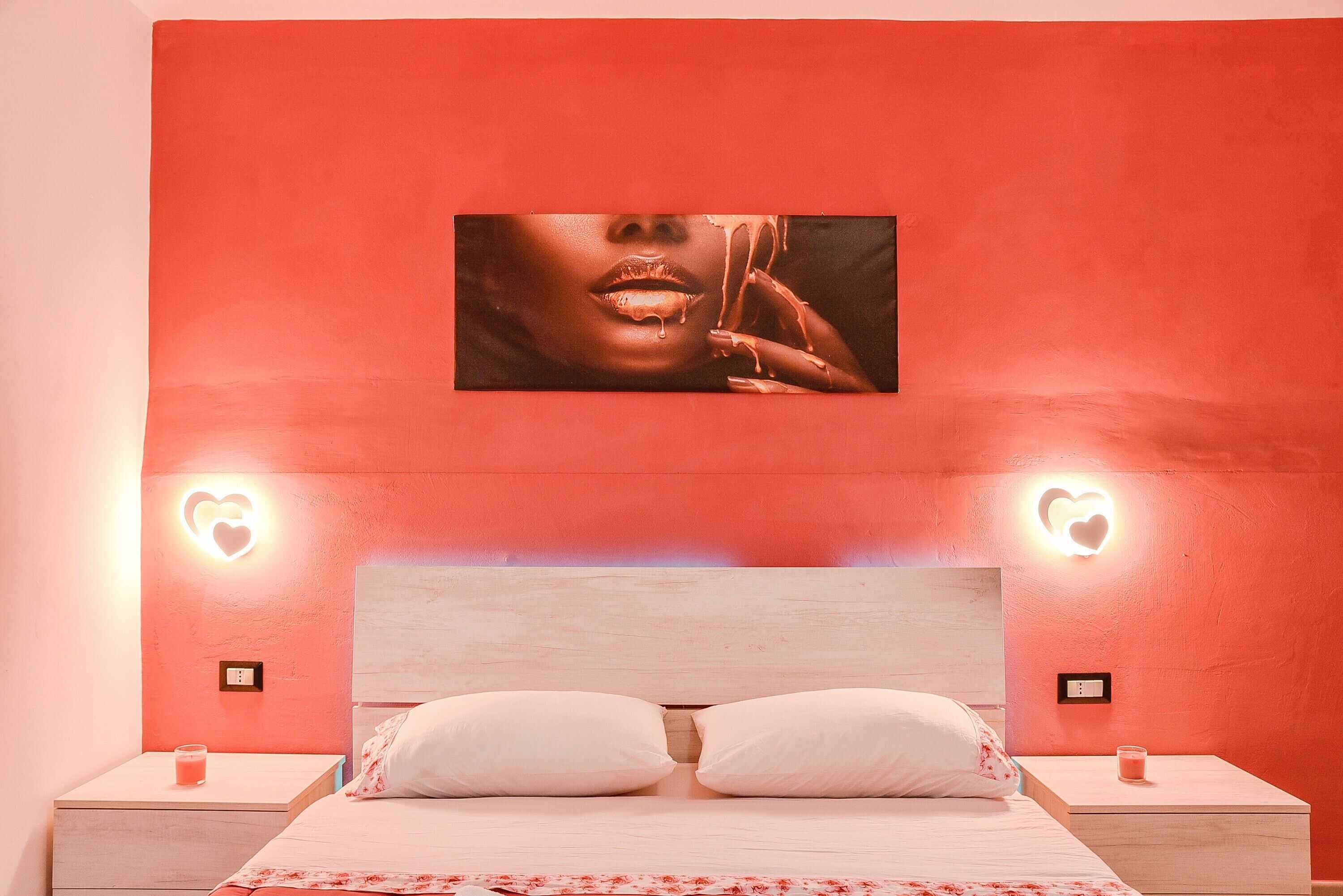 A bedroom with a large bed, two bedside tables, and a wall-mounted picture.
