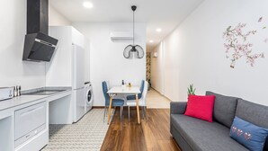 A modern kitchen with a dining area, a gray sofa with red and blue cushions, and a wall-mounted air conditioner. - Holiday Home 'Portal A Valencia' with Wi-Fi and Air Conditioning (València)