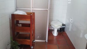 Un baño pequeño con un estante de madera que sostiene un rollo de papel higiénico y una planta pequeña.