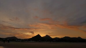 Un atardecer sobre un paisaje montañoso con una playa en primer plano.