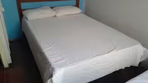 Una cama individual con cabecera de madera en una habitación con paredes azules.