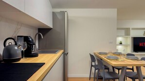 Een moderne keuken met een koffieapparaat, waterkoker en een eethoek met een tafel gedekt voor twee personen.