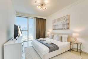 A modern hotel room with a large bed, a television, a city view, and a painting on the wall. - PVH - Boulevard Point 2BR - Dubai Mall (Dubai)