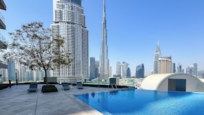 Pool på taget med liggestole og udsigt til Burj Khalifa og omkringliggende skyskraber.