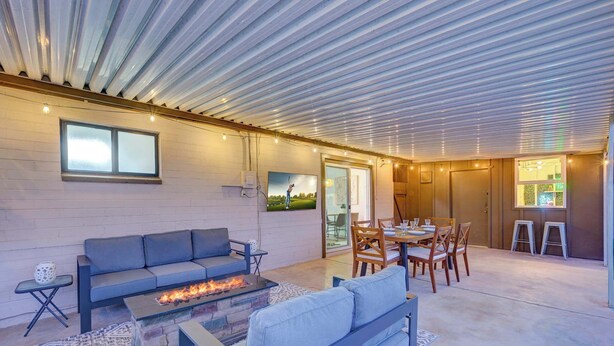 A spacious indoor area with a stone fireplace, a blue sofa, and a dining table with chairs. - Scottsdale Oasis | Pool, Firepit, Putting Green (Scottsdale)