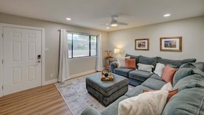 A living room with a grey sofa, ottoman, and a ceiling fan. - Scottsdale Oasis | Pool, Firepit, Putting Green (Scottsdale)