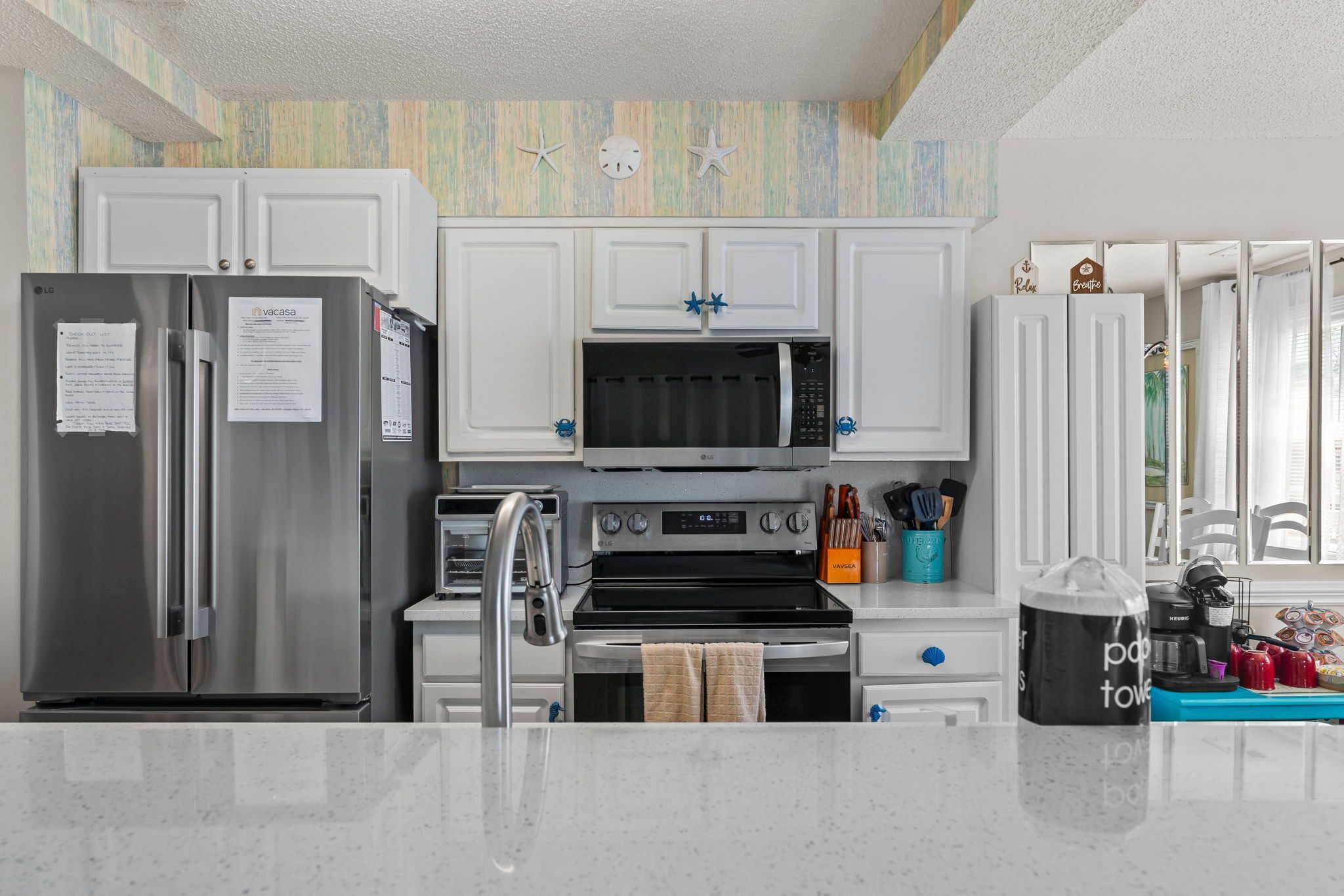 A modern kitchen with white cabinets, stainless steel appliances, and a microwave.