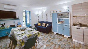 Un espacio habitable compacto con comedor, sofá, kitchenette y televisor.