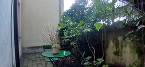 A small outdoor area with a green table and chairs, a potted plant, and a wall with climbing plants. - Modern 3BDR Home Heart of The Liberties (Dublin)