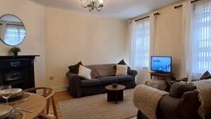 A living room with a sofa, a television, a fireplace, and a dining area with a table and chairs. - Modern 3BDR Home Heart of The Liberties (Dublin)