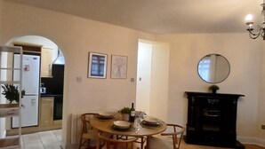 A dining area with a round table, chairs, a chandelier, and a fireplace. - Modern 3BDR Home Heart of The Liberties (Dublin)