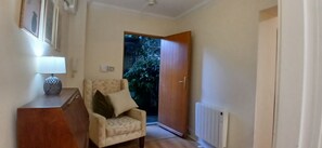 A hallway with a chair, a lamp, and a door leading to a garden. - Modern 3BDR Home Heart of The Liberties (Dublin)
