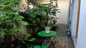 A small outdoor seating area with a table and chairs, surrounded by dense foliage. - Modern 3BDR Home Heart of The Liberties (Dublin)