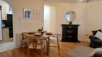 A dining area with a table set for four, a fireplace, and a sofa in a living room.